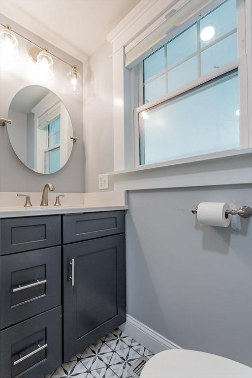 half bath with vanity, toilet, and baseboards