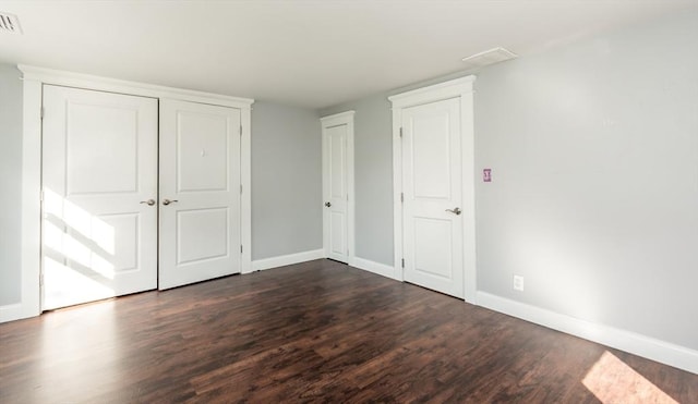 unfurnished bedroom featuring dark wood-type flooring, visible vents, and baseboards