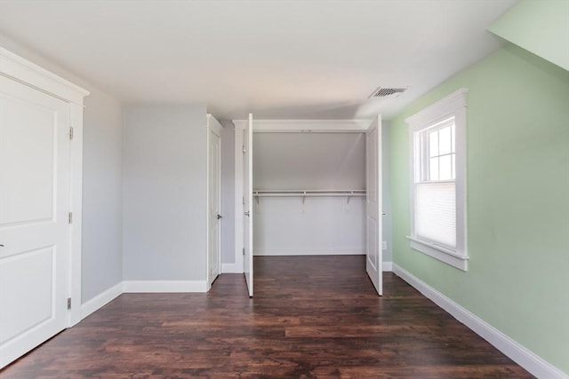 unfurnished bedroom featuring a closet, visible vents, baseboards, and wood finished floors