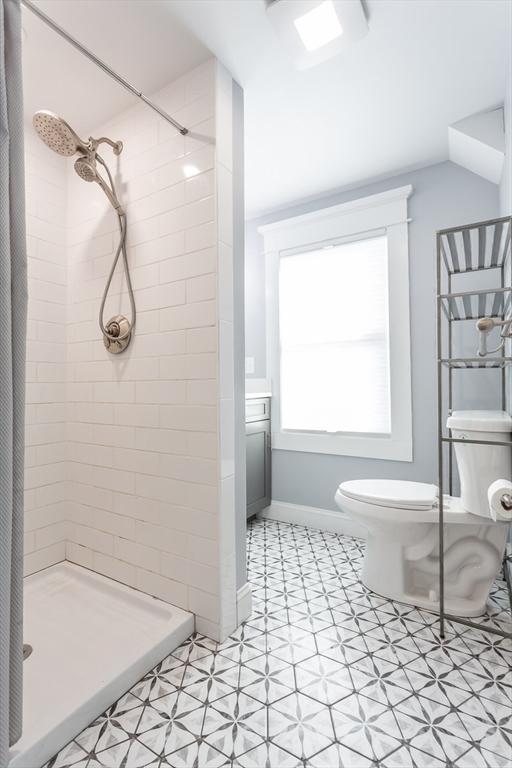 full bathroom with a shower stall, toilet, and baseboards