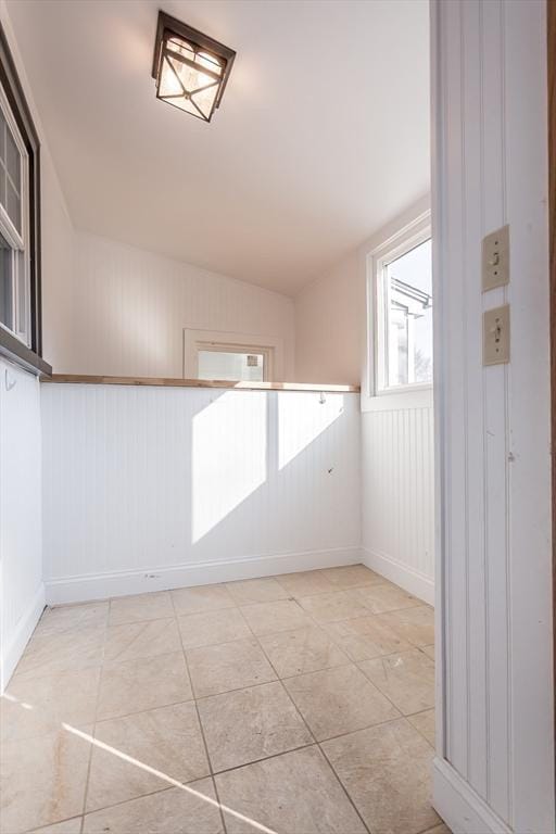 empty room featuring light tile patterned floors, baseboards, and vaulted ceiling