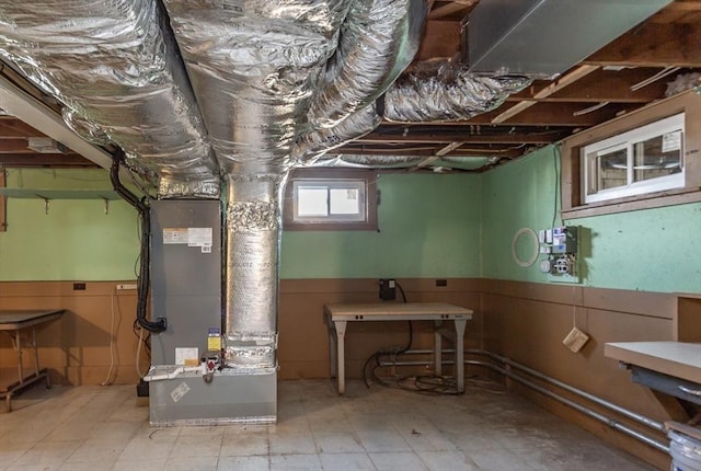 below grade area with tile patterned floors, heating unit, and wainscoting