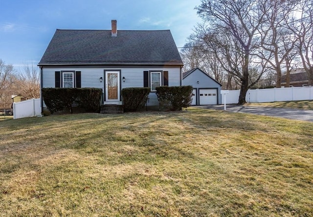 view of front of house featuring fence, roof with shingles, entry steps, a front lawn, and a detached garage