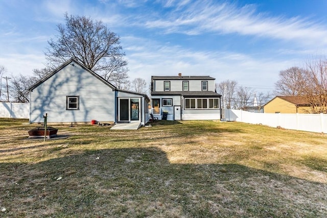 rear view of property featuring a lawn, fence, and a sunroom