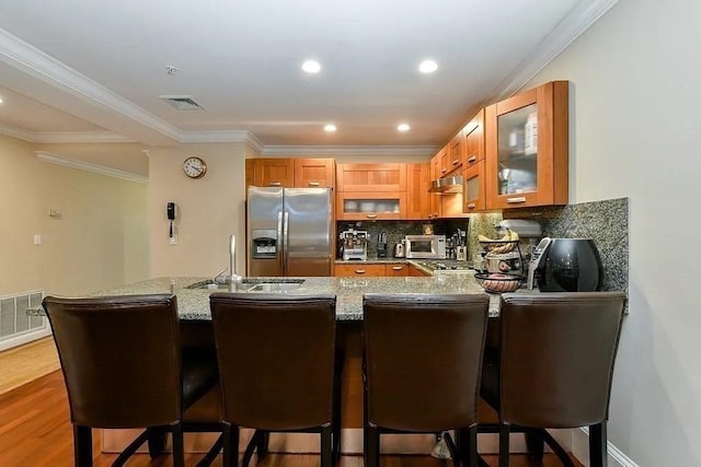 19 Bay State Rd Unit 1, Boston, MA 02215 - kitchen with stainless steel fridge, a sink, glass insert cabinets, brown cabinets, and light stone counters