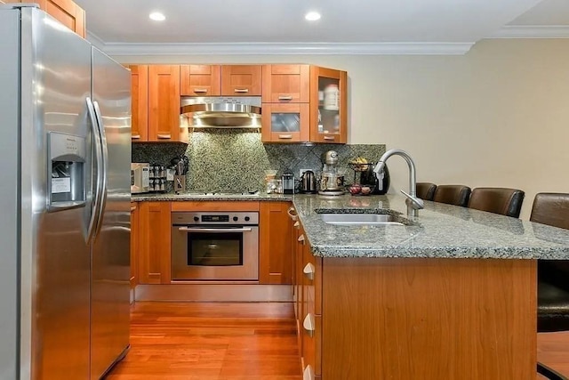 19 Bay State Rd Unit 1, Boston, MA 02215 - kitchen featuring stainless steel appliances, a sink, exhaust hood, a peninsula, and brown cabinets