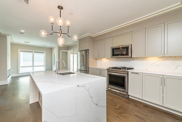 kitchen with appliances with stainless steel finishes, sink, decorative backsplash, an island with sink, and dark wood-type flooring