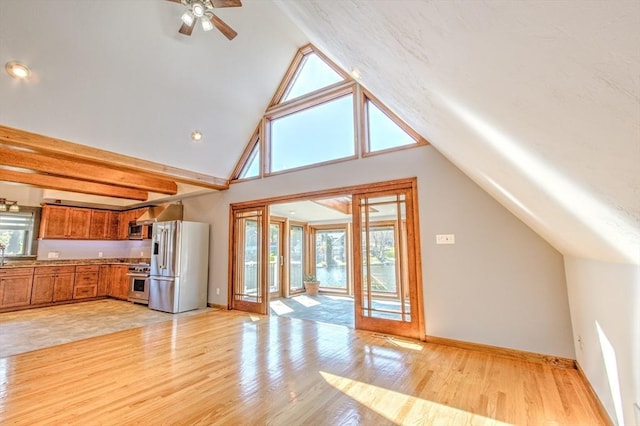 interior space with a ceiling fan, brown cabinets, lofted ceiling, light wood-style floors, and stainless steel appliances