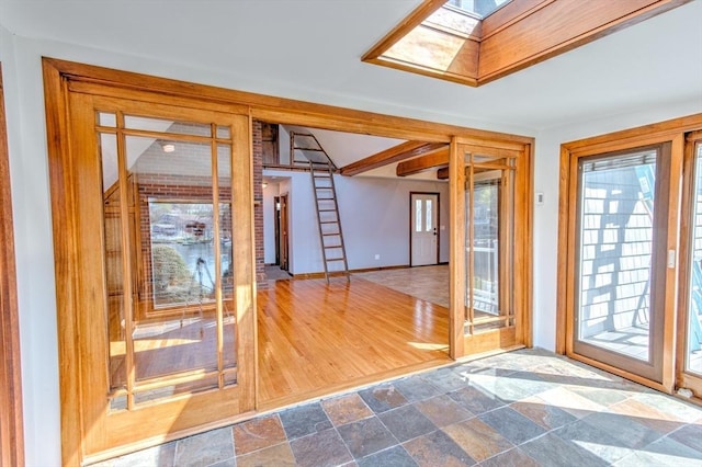 interior space with a skylight, baseboards, and stone finish flooring
