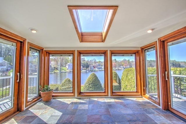 unfurnished sunroom featuring a water view, a skylight, and stone finish flooring