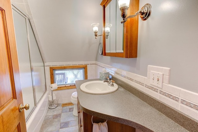 full bath with toilet, bath / shower combo with glass door, and vanity