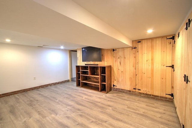 finished basement featuring recessed lighting, baseboards, wood walls, and wood finished floors
