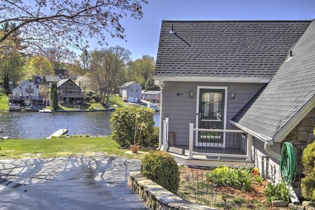 exterior space with roof with shingles and a water view
