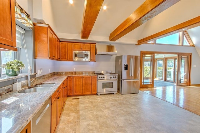 kitchen featuring beam ceiling, light stone countertops, under cabinet range hood, a sink, and stainless steel appliances