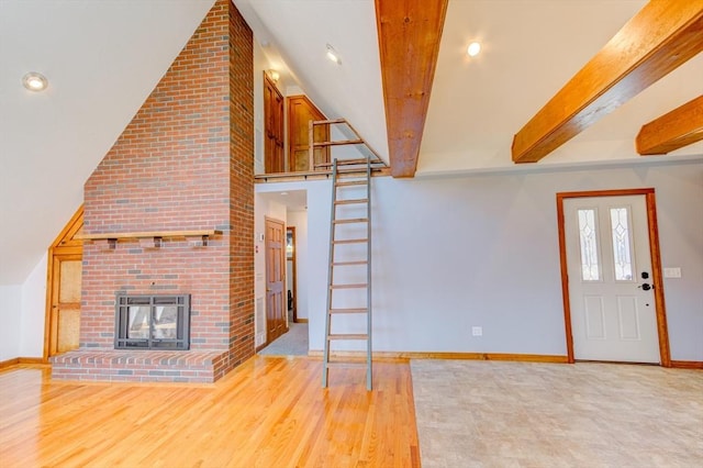 unfurnished living room featuring a fireplace, baseboards, lofted ceiling with beams, and wood finished floors