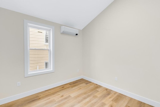 unfurnished room with light wood-style floors, baseboards, vaulted ceiling, and an AC wall unit