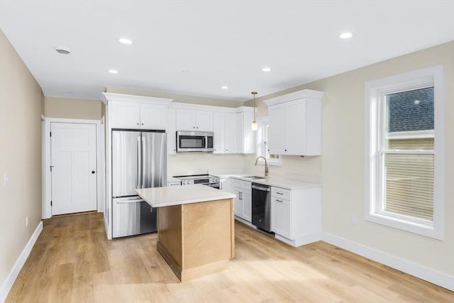 kitchen with appliances with stainless steel finishes, light countertops, white cabinets, and a sink