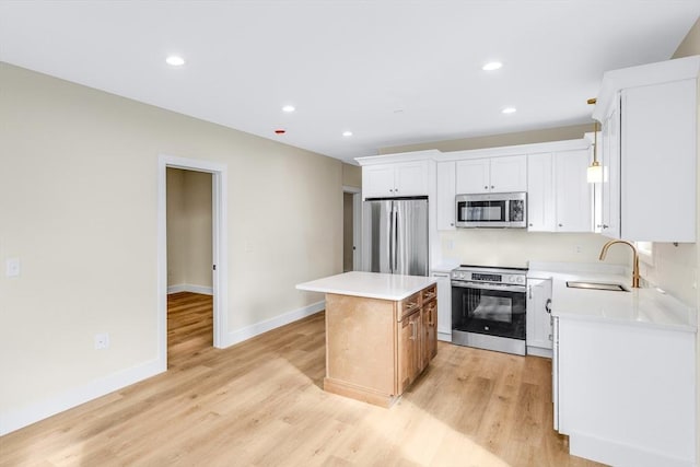 kitchen featuring appliances with stainless steel finishes, a center island, light countertops, light wood-type flooring, and a sink