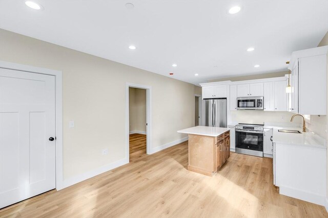 kitchen featuring light wood-type flooring, stainless steel appliances, a sink, and a center island