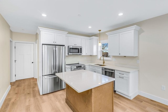 kitchen featuring appliances with stainless steel finishes, light wood-style floors, white cabinetry, and a sink