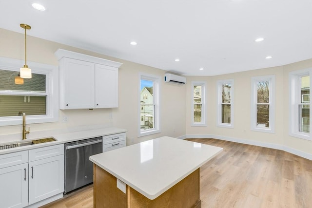 kitchen with light countertops, an AC wall unit, white cabinets, a sink, and dishwasher