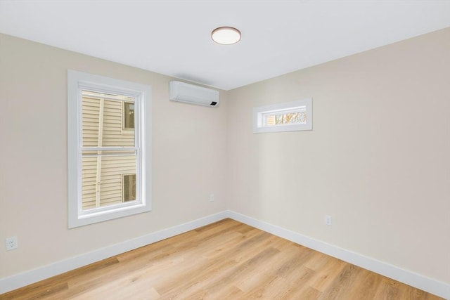 empty room with light wood-type flooring, baseboards, and a wall mounted AC