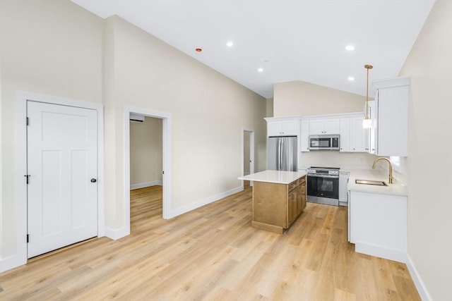 kitchen featuring a center island, stainless steel appliances, light countertops, light wood-style flooring, and a sink