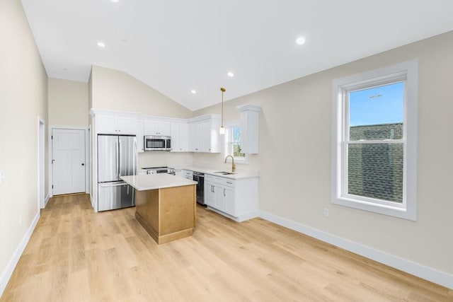 kitchen featuring stainless steel appliances, a sink, white cabinetry, light countertops, and a center island