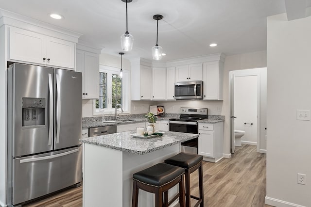 kitchen with white cabinetry, a center island, stainless steel appliances, and sink