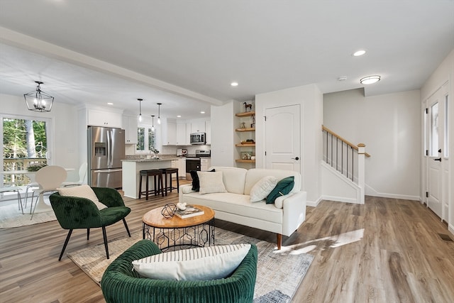 living room with light hardwood / wood-style flooring, a chandelier, and sink