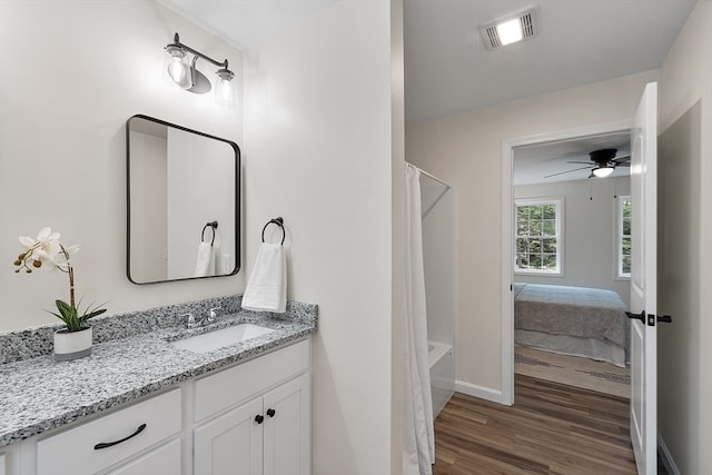 bathroom featuring hardwood / wood-style flooring, vanity, ceiling fan, and shower / tub combo