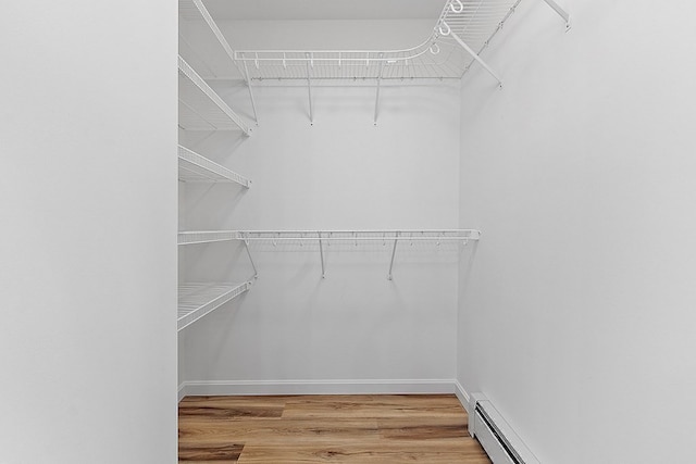 spacious closet featuring hardwood / wood-style floors and a baseboard radiator