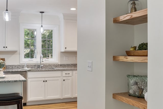 kitchen featuring light wood-type flooring, decorative light fixtures, and white cabinetry