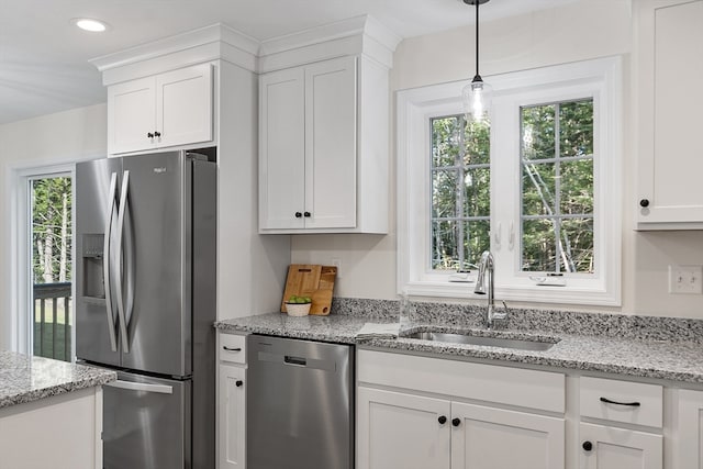 kitchen with light stone countertops, appliances with stainless steel finishes, white cabinetry, and sink