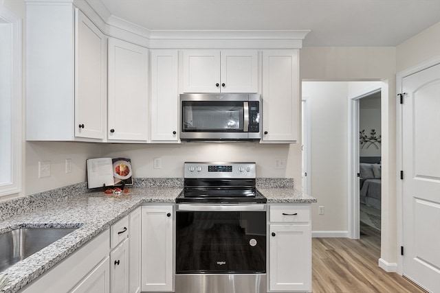 kitchen with white cabinetry, light hardwood / wood-style flooring, stainless steel appliances, and light stone counters