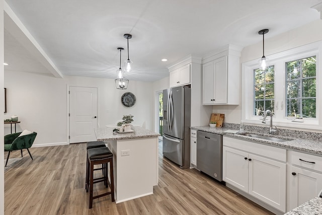 kitchen with white cabinets, appliances with stainless steel finishes, a center island, and light hardwood / wood-style floors