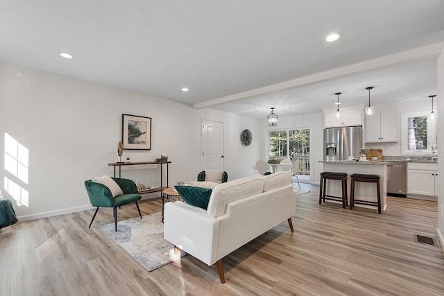 living room with light hardwood / wood-style floors and an inviting chandelier