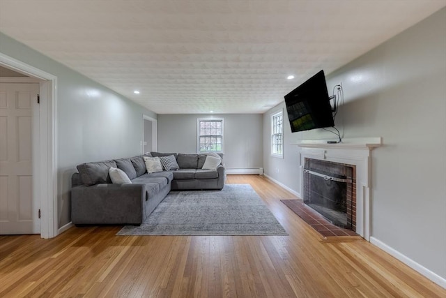 9 Brucewood, Acton, MA 01720 - living room with wood finished floors, baseboards, a fireplace with raised hearth, a baseboard heating unit, and recessed lighting
