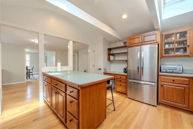 9 Brucewood, Acton, MA 01720 - kitchen with a breakfast bar area, brown cabinets, light countertops, freestanding refrigerator, and light wood-style floors