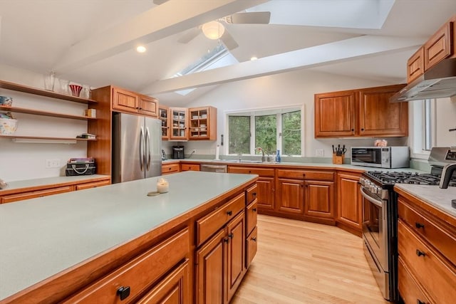 9 Brucewood, Acton, MA 01720 - kitchen featuring lofted ceiling with skylight, under cabinet range hood, brown cabinets, a sink, and stainless steel appliances