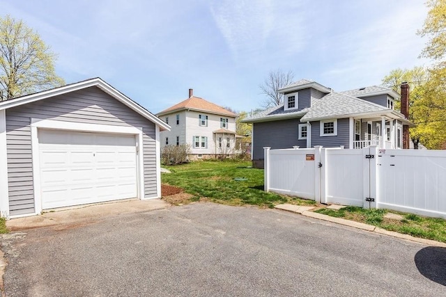 detached garage with a gate, aphalt driveway, and fence