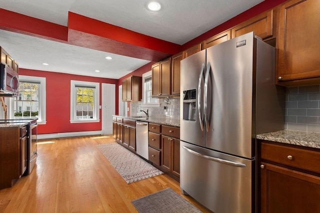 kitchen featuring a sink, appliances with stainless steel finishes, light wood-style flooring, and tasteful backsplash