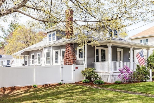 view of front of home featuring fence, a porch, and a front lawn