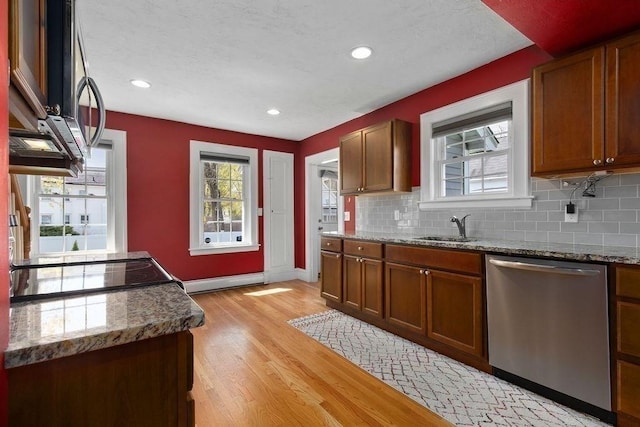 kitchen featuring a sink, light wood-style flooring, appliances with stainless steel finishes, and backsplash