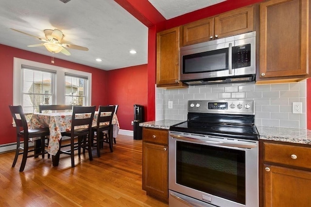 kitchen featuring stainless steel appliances, brown cabinetry, and light wood-style floors