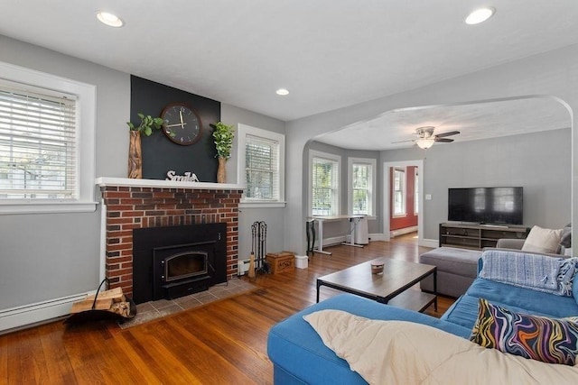 living room with a fireplace, arched walkways, recessed lighting, baseboards, and wood finished floors