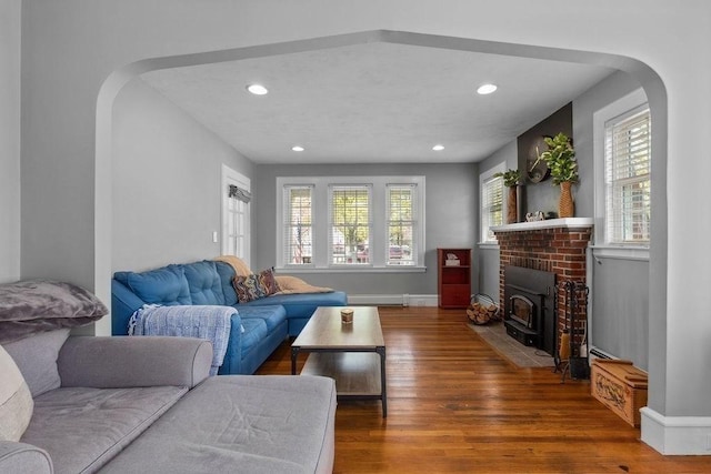 living room featuring arched walkways, plenty of natural light, and wood finished floors
