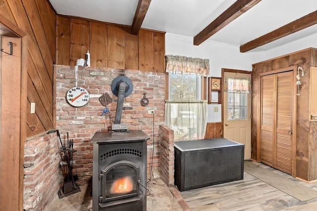 room details featuring a wood stove, wooden walls, and beam ceiling