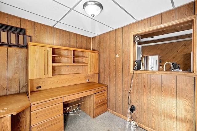 unfurnished office featuring wooden walls, built in desk, and carpet floors