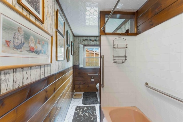 bathroom featuring  shower combination, wainscoting, toilet, and wallpapered walls